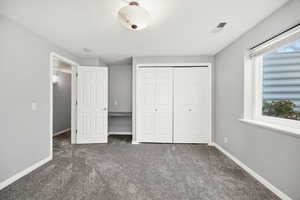 Unfurnished bedroom with dark carpet and a closet