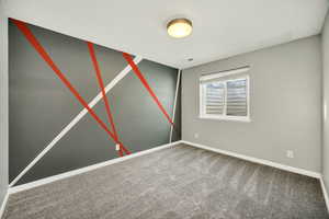 Carpeted empty bedroom featuring baseboards and an accent wall