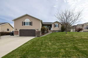 View of front of property with a front yard, concrete driveway, a garage, and vinyl and brick siding