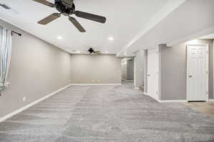 Unfurnished living room with arched walkways, light colored carpet, ceiling fan, and recessed lighting