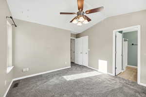 Unfurnished bedroom with lofted ceiling, carpet floors, ceiling fan, and connected bathroom