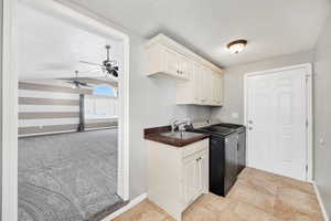 Washroom with cabinet space, light colored carpet, vaulted ceiling, a textured ceiling, and ceiling fan