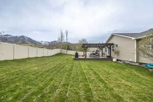 Fenced backyard featuring a deck with mountain view and a pergola