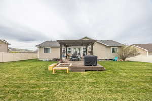 Rear view of house with a fenced backyard, a deck, and an outdoor fire pit