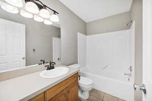 Full bath with vanity, washtub / shower combination, and light tile patterned floors