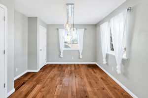 Unfurnished dining area with hardwood / wood-style flooring and a chandelier