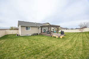 Rear view of property with a fenced backyard, a deck, a pergola, and a fire pit