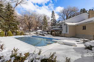 Snow covered pool with a patio, an outdoor pool, a gazebo, a diving board, and a balcony