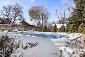 Snow covered pool with a fenced backyard
