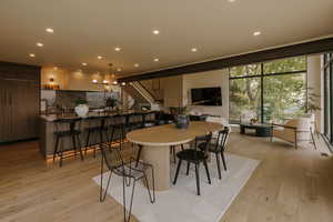 Dining space featuring floor to ceiling windows, light wood-type flooring, recessed lighting, and stairs