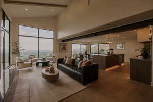 Living area with dark wood-style floors, recessed lighting, high vaulted ceiling, and a water view