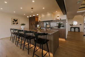 Kitchen featuring modern cabinets, decorative backsplash, a spacious island, a breakfast bar area, and dark stone countertops