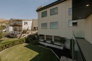 Back of property with a lawn, board and batten siding, and a balcony
