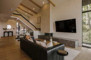 Living room featuring beamed ceiling, light wood-style floors, plenty of natural light, and a towering ceiling
