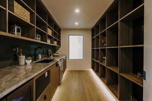 Interior space featuring built in microwave, light wood-type flooring, dark countertops, dishwasher, and dark brown cabinetry