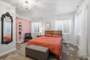 Carpeted bedroom featuring baseboards and a chandelier