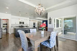 Dining room featuring a chandelier, a raised ceiling, dark wood finished floors, recessed lighting, and a barn door