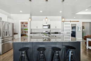 Kitchen with a barn door, stainless steel appliances, dark wood-style floors, dark stone counters, and recessed lighting