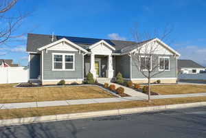 View of front of house with solar panels, covered porch, and a shingled roof