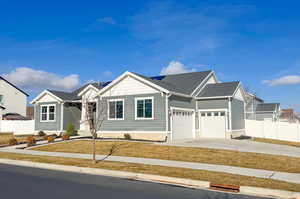 View of front facade featuring driveway, roof with shingles, and a garage