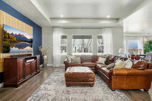 Living area featuring a tray ceiling, dark wood-style flooring, and a chandelier