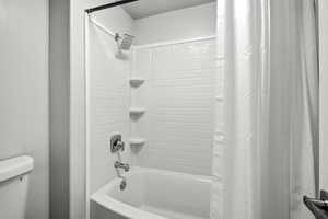 Full bathroom featuring shower / bath combination with curtain and toilet