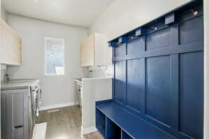 Laundry room, mud room, featuring light wood-style floors, washing machine and dryer, and cabinet space