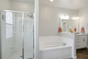Full bathroom with vanity, a bath, a stall shower, and dark wood-type flooring