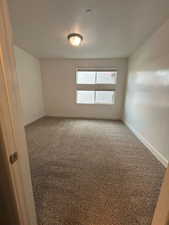 Carpeted empty room featuring a textured ceiling and baseboards