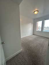 Carpeted spare room with baseboards and a textured ceiling