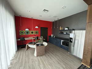 Kitchen with stainless steel appliances, open shelves, dark countertops, light wood finished floors, and hanging light fixtures