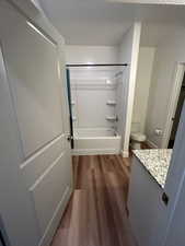 Full bath with shower / tub combination, vanity, and dark wood-type flooring