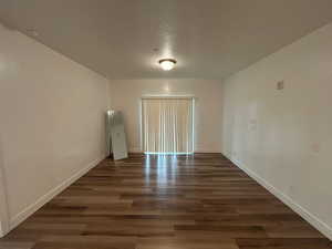 Empty room with dark wood-style flooring and a textured ceiling