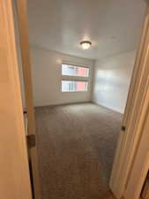 Carpeted spare room with a textured ceiling and baseboards