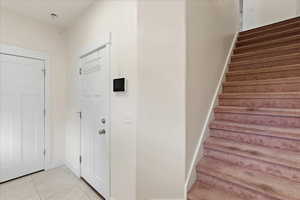 Foyer featuring light tile patterned floors and stairs