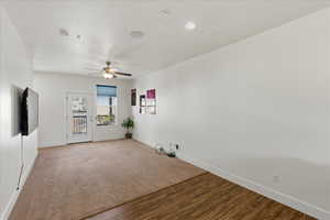 Empty room with carpet, wood finished floors, and ceiling fan