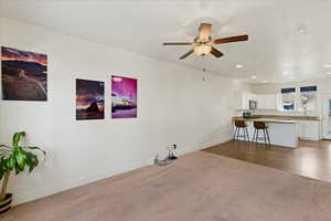 Living area with dark colored carpet, a ceiling fan, and recessed lighting