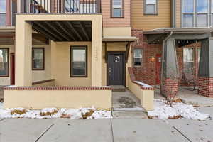 Snow covered property entrance with brick siding
