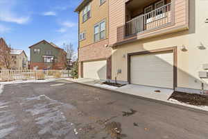 Exterior space featuring a garage, stucco siding, a residential view, brick siding, and driveway