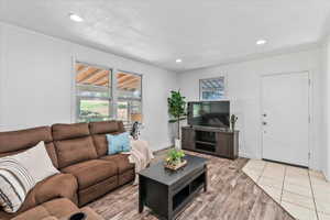 Living room with light wood-style floors, recessed lighting, and ornamental molding