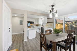 Dining space with a chandelier, light wood-style floors, electric panel, and recessed lighting