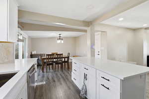 Kitchen featuring white cabinets, dark wood finished floors, hanging light fixtures, a kitchen island, and recessed lighting