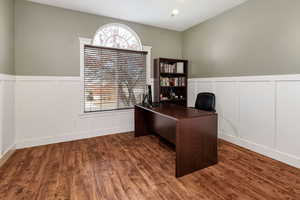 Office area with dark wood-type flooring, a wainscoted wall, and a decorative wall
