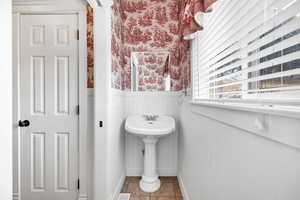 Bathroom featuring wallpapered walls, wainscoting, and light tile patterned floors