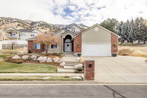 View of front of house with concrete driveway, brick siding, a mountain view, and stucco siding