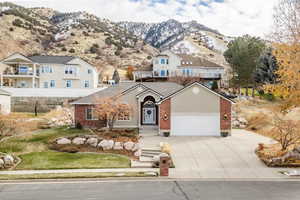 View of front of home with brick siding, concrete driveway, a mountain view, and an attached garage