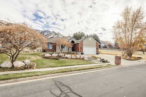 View of front of house featuring brick siding, a front lawn, driveway, an attached garage, and a mountain view