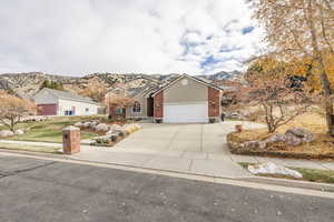 View of front of home featuring brick siding, concrete driveway, a garage, and a mountain view