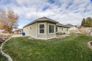 Rear view of house with stucco siding, a lawn, a patio, and roof with shingles