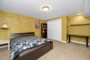 Bedroom with a textured wall, a closet, and light colored carpet